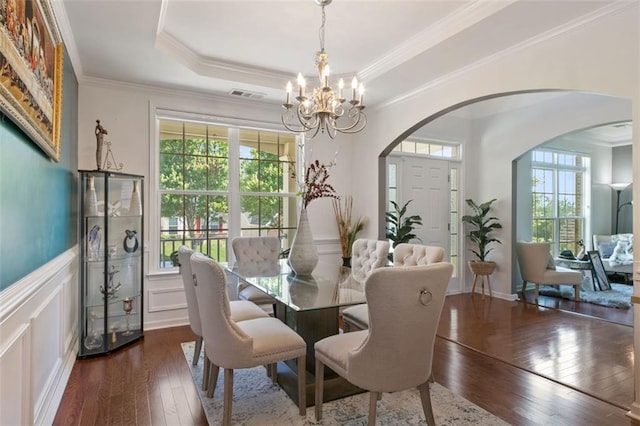 829 Castlebottom Dr, Lawrenceville, GA 30045 - dining area with arched walkways, dark wood-style flooring, a chandelier, crown molding, and a decorative wall