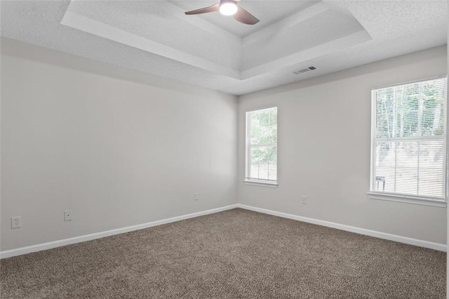 carpeted empty room featuring ceiling fan, a raised ceiling, and a textured ceiling