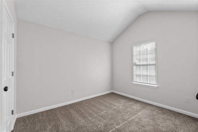 empty room featuring carpet flooring, a textured ceiling, and vaulted ceiling