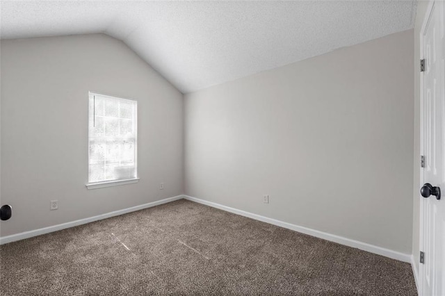 spare room with a textured ceiling, lofted ceiling, and carpet floors