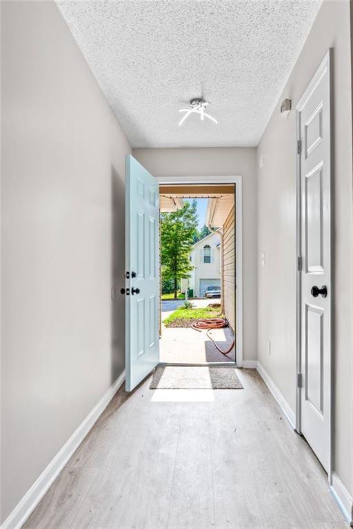 doorway with light hardwood / wood-style floors and a textured ceiling