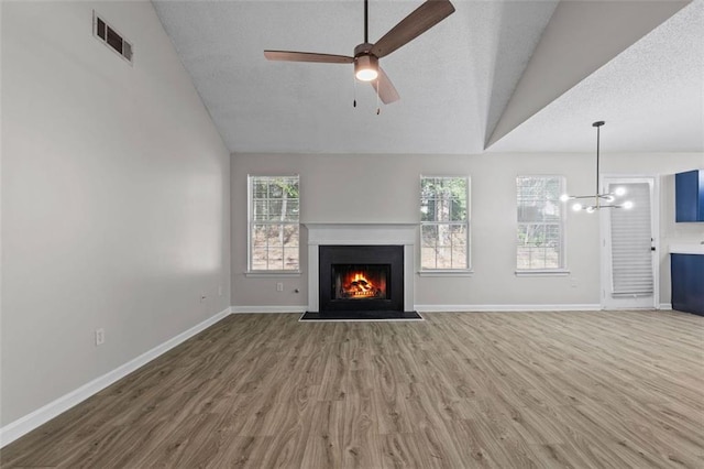 unfurnished living room with ceiling fan with notable chandelier, a textured ceiling, hardwood / wood-style flooring, and lofted ceiling