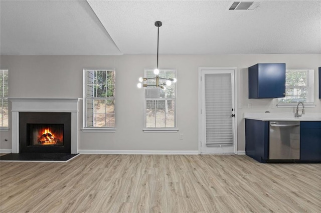 kitchen with blue cabinetry, dishwasher, a notable chandelier, pendant lighting, and light hardwood / wood-style floors