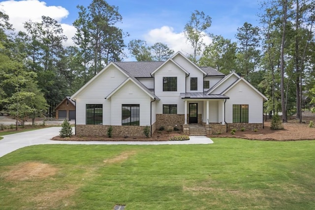 modern farmhouse featuring a standing seam roof, roof with shingles, metal roof, and a front yard