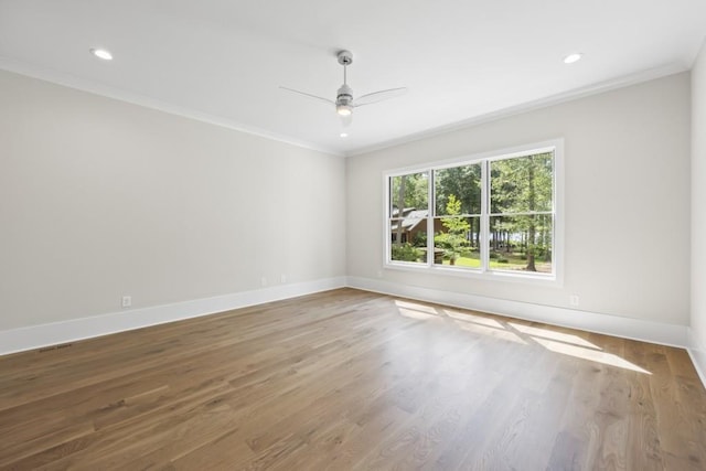 spare room featuring baseboards, wood finished floors, and crown molding