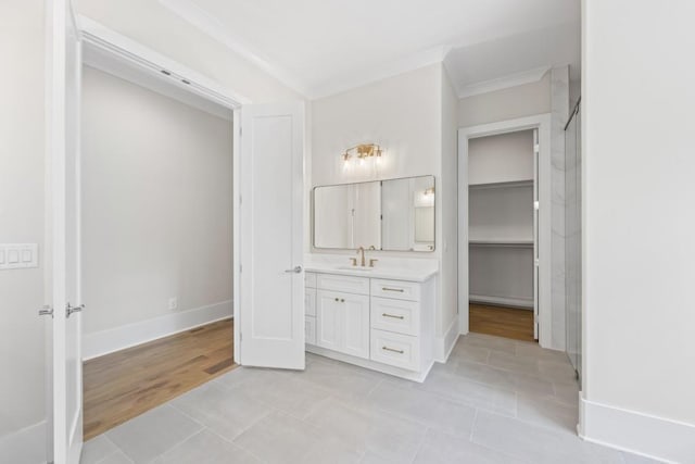 full bathroom featuring a walk in closet, ornamental molding, vanity, baseboards, and tile patterned floors