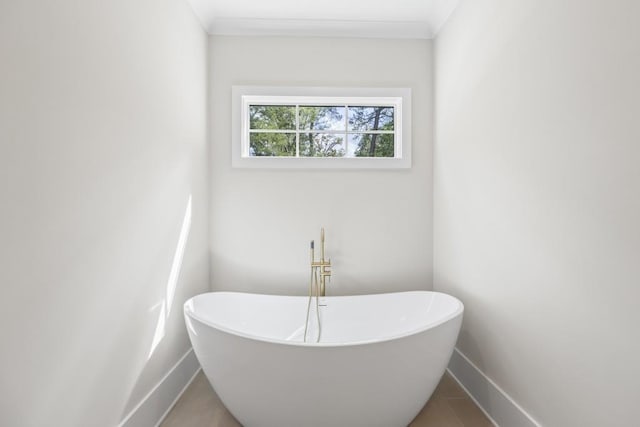 bathroom featuring a freestanding bath, crown molding, and baseboards