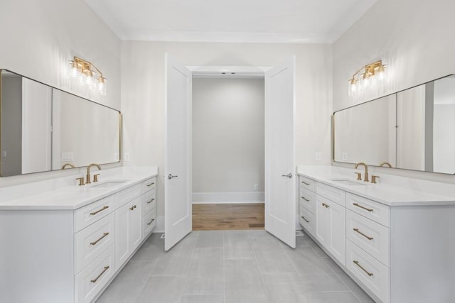 bathroom with tile patterned flooring, baseboards, two vanities, and a sink