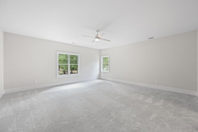 spare room with a ceiling fan, light carpet, visible vents, and baseboards