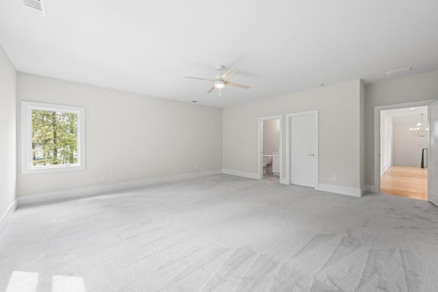 unfurnished bedroom featuring light colored carpet, connected bathroom, visible vents, and baseboards