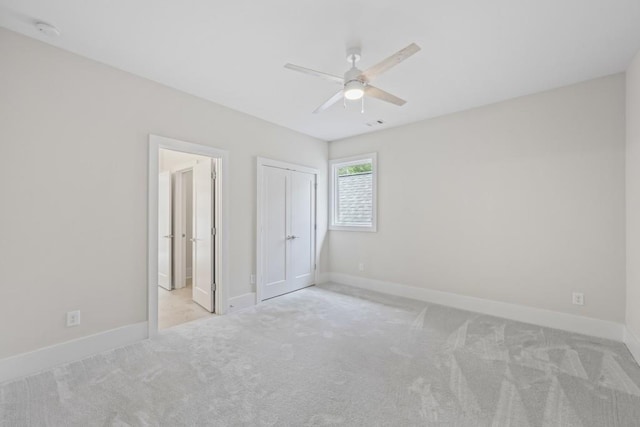 unfurnished bedroom featuring a closet, light colored carpet, ceiling fan, and baseboards