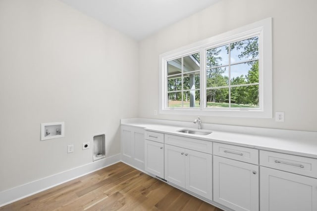 clothes washing area featuring hookup for an electric dryer, washer hookup, a sink, cabinet space, and light wood finished floors