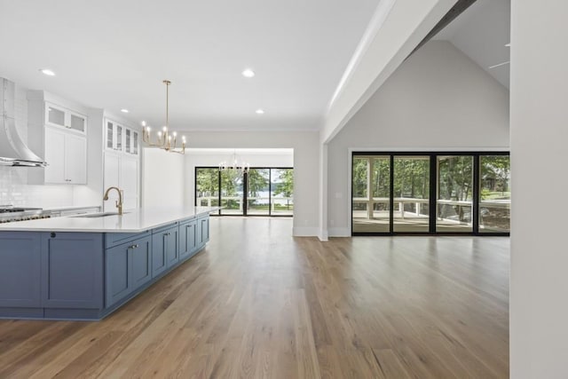 kitchen featuring a chandelier, a sink, white cabinets, light countertops, and glass insert cabinets