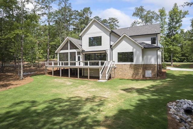 back of house featuring a shingled roof, a sunroom, a lawn, and stairway