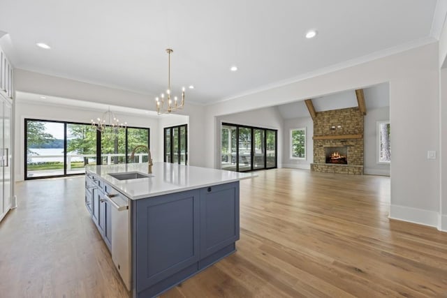 kitchen with a center island with sink, open floor plan, light countertops, pendant lighting, and a sink