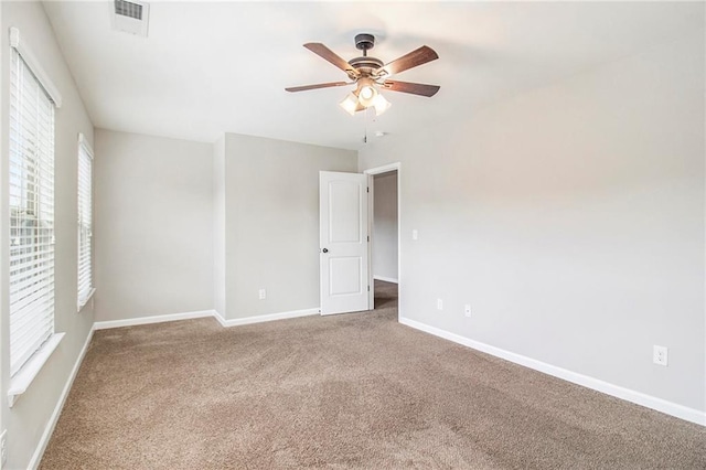 carpeted empty room with visible vents, baseboards, and a ceiling fan