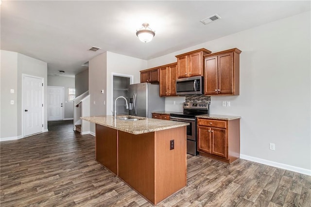 kitchen featuring brown cabinets, visible vents, appliances with stainless steel finishes, and a sink