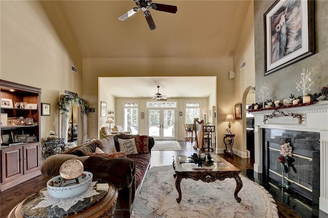 living room featuring ceiling fan, dark hardwood / wood-style flooring, a premium fireplace, and french doors