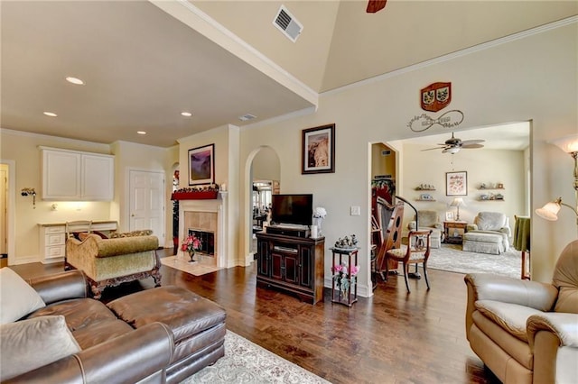 living room featuring a tile fireplace, ceiling fan, dark hardwood / wood-style flooring, and ornamental molding