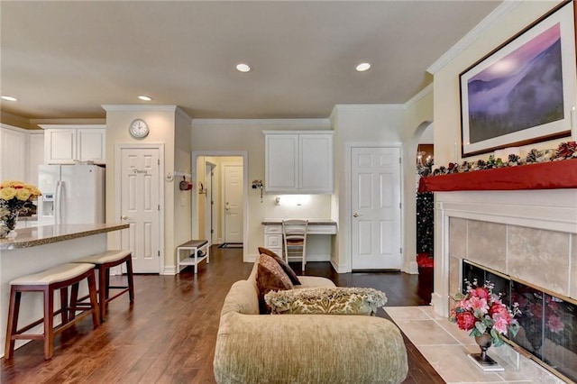 living room featuring crown molding, a tile fireplace, and dark wood-type flooring