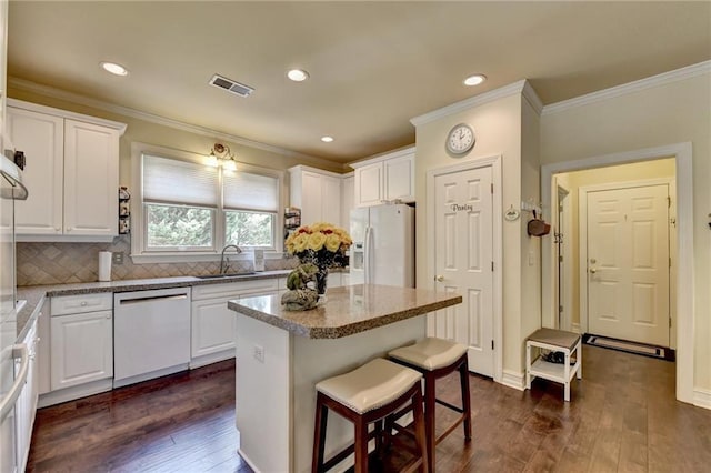 kitchen featuring tasteful backsplash, white cabinetry, a kitchen island, and white appliances