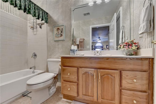 full bathroom with ceiling fan, tile patterned flooring, toilet, vanity, and tiled shower / bath