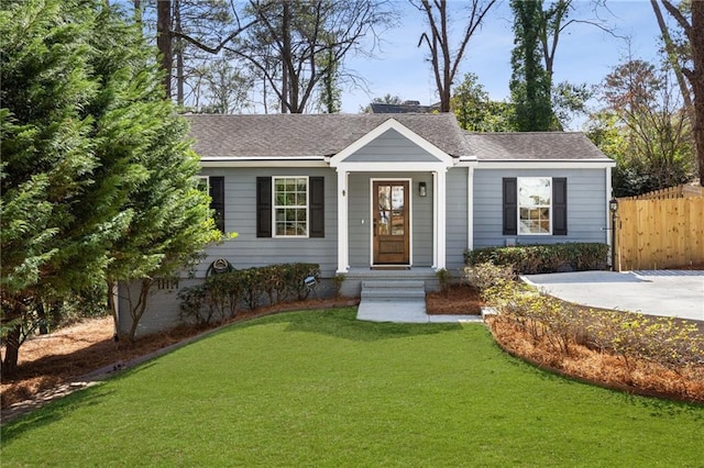 ranch-style house with a shingled roof, fence, and a front yard