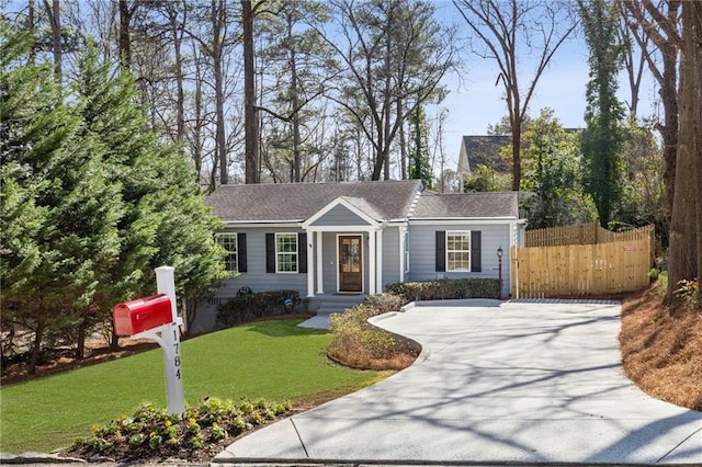 ranch-style house featuring driveway, a front lawn, and fence