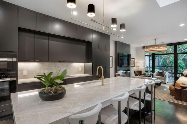 kitchen featuring a sink, decorative backsplash, gray cabinets, floor to ceiling windows, and hanging light fixtures