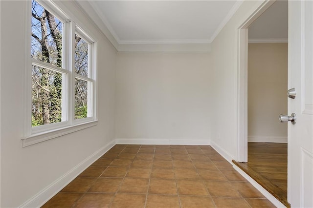 tiled empty room featuring crown molding and baseboards