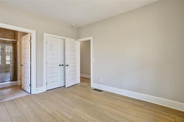 unfurnished bedroom featuring visible vents, a closet, light wood-style flooring, and baseboards