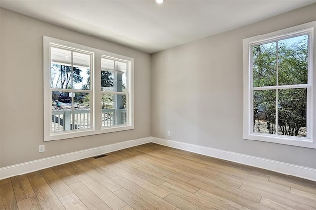 unfurnished room featuring wood finished floors, visible vents, and baseboards