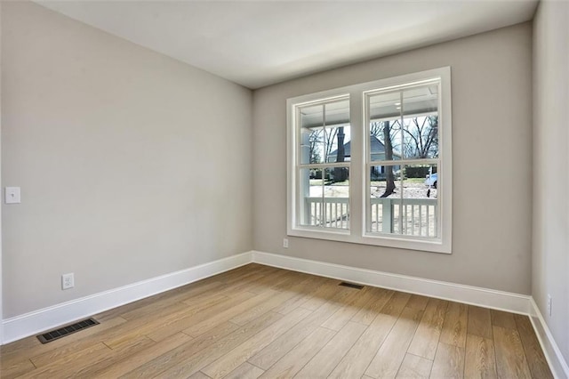 empty room featuring baseboards, visible vents, and wood finished floors