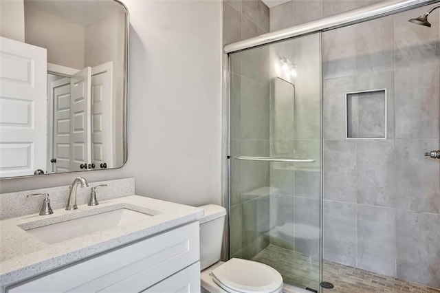 full bathroom featuring vanity, a shower stall, and toilet