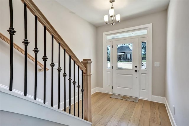 foyer entrance featuring a chandelier, stairway, light wood-type flooring, and baseboards