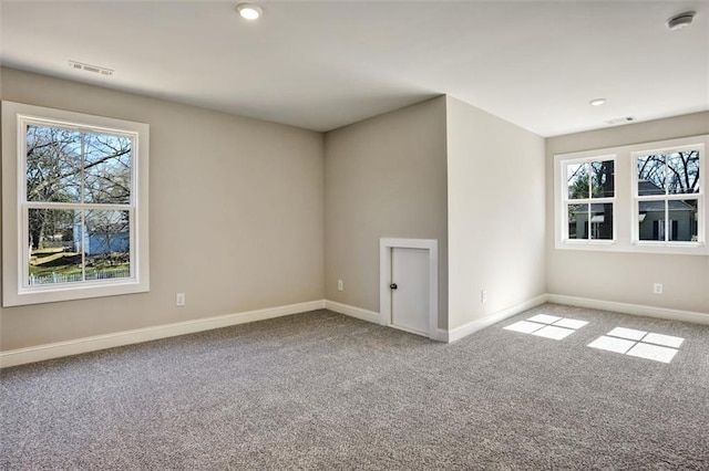 carpeted spare room with visible vents and baseboards