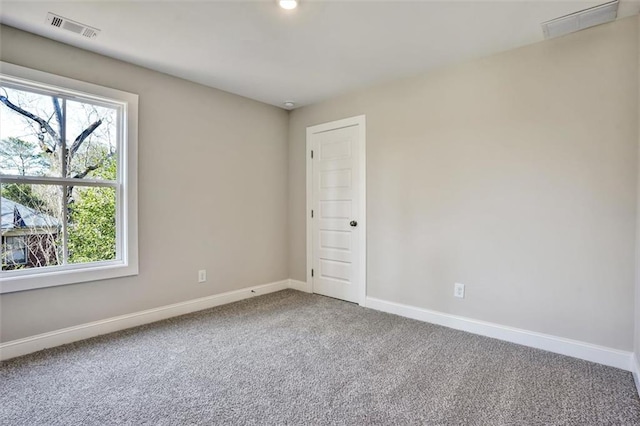 spare room featuring baseboards, plenty of natural light, visible vents, and carpet flooring