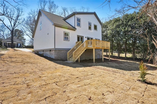 rear view of property featuring stairs, roof with shingles, and a wooden deck