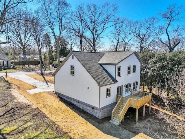 view of side of property featuring a shingled roof, stairs, and a deck