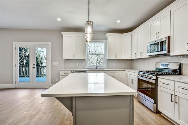 kitchen featuring light wood-style flooring, stainless steel appliances, a kitchen island, a sink, and decorative backsplash