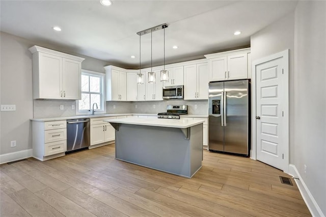 kitchen with stainless steel appliances, tasteful backsplash, light wood-type flooring, and light countertops