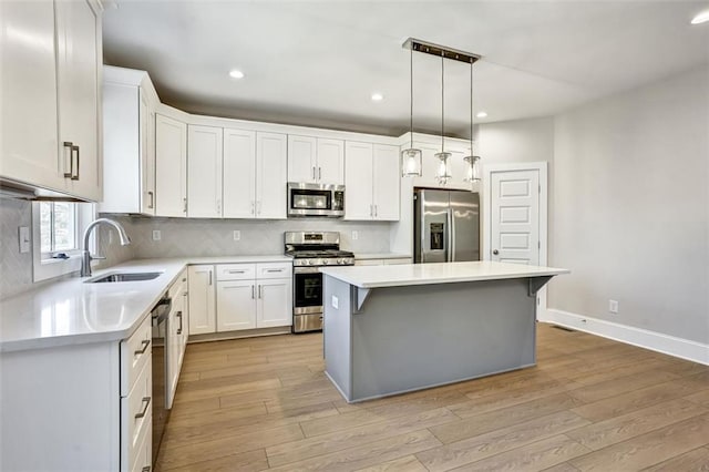 kitchen featuring light wood-type flooring, tasteful backsplash, stainless steel appliances, and a sink