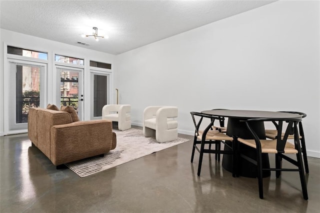 interior space featuring baseboards, visible vents, a textured ceiling, and finished concrete flooring