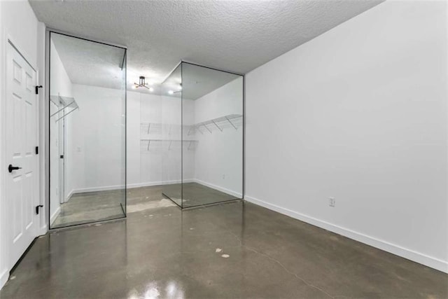 interior space with baseboards, concrete floors, a textured ceiling, and a closet