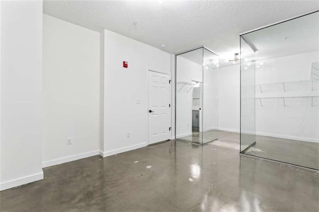 unfurnished bedroom featuring baseboards, a textured ceiling, and finished concrete flooring