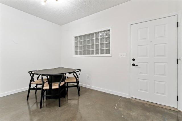 dining space featuring baseboards, concrete floors, and a textured ceiling
