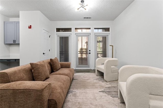 living area featuring a textured ceiling and visible vents