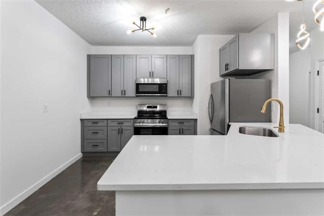 kitchen featuring appliances with stainless steel finishes, baseboards, gray cabinetry, and a sink