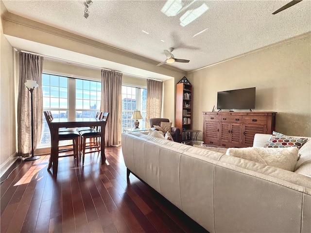 living room featuring dark wood-type flooring, crown molding, a textured ceiling, and ceiling fan