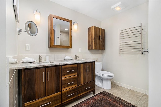 bathroom with double vanity, toilet, radiator heating unit, tile patterned flooring, and a sink